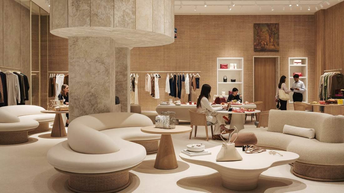 Retail interior with curved cream seating, clothing rails and a styled display table